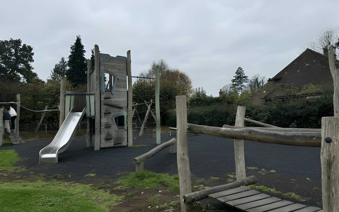 Bespoke timber playground equipment featuring a natural wood climbing tower, stainless steel slide, and graduated challenge balance beams on a safety-surfaced school site